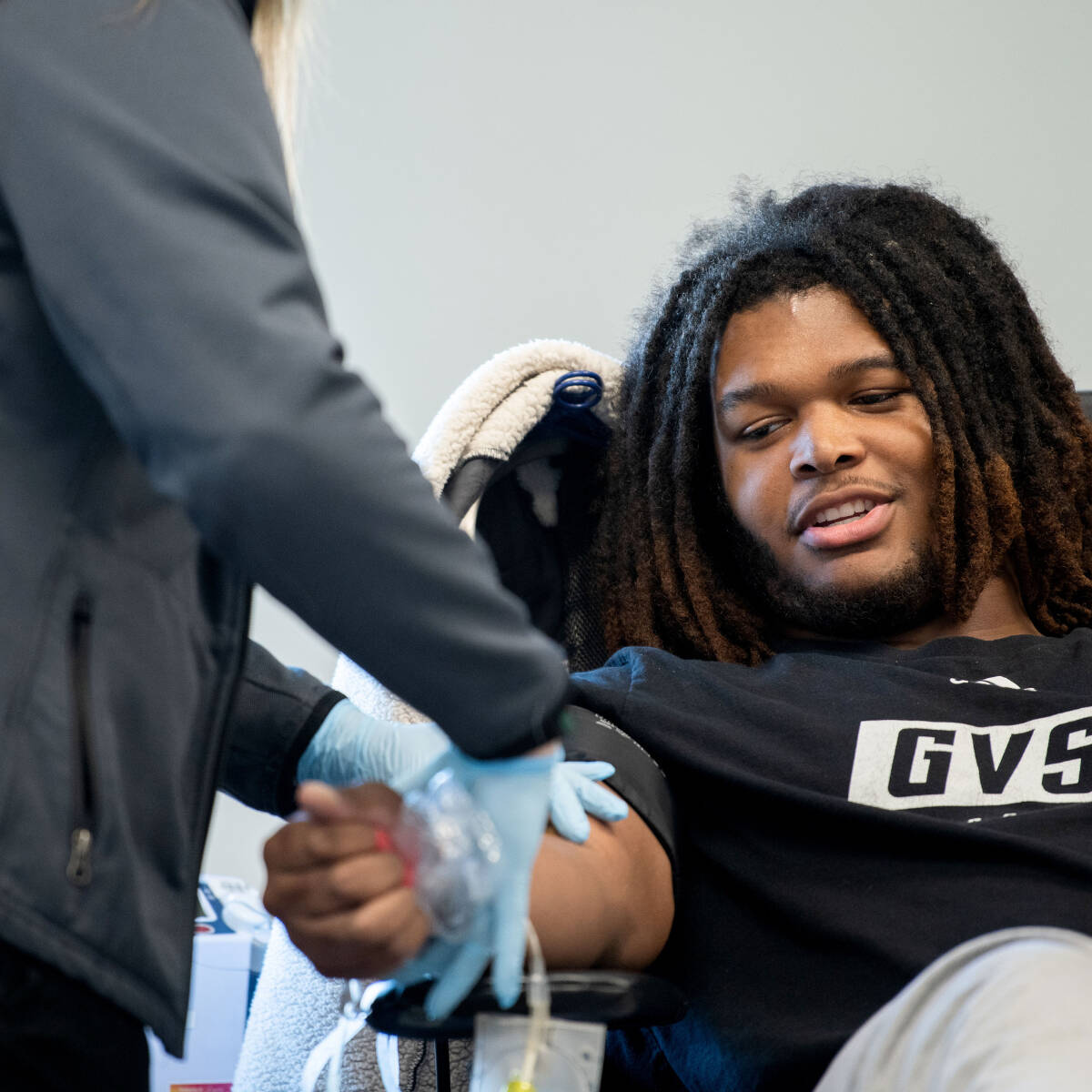 A student sitting in a chair and getting their blood drawn